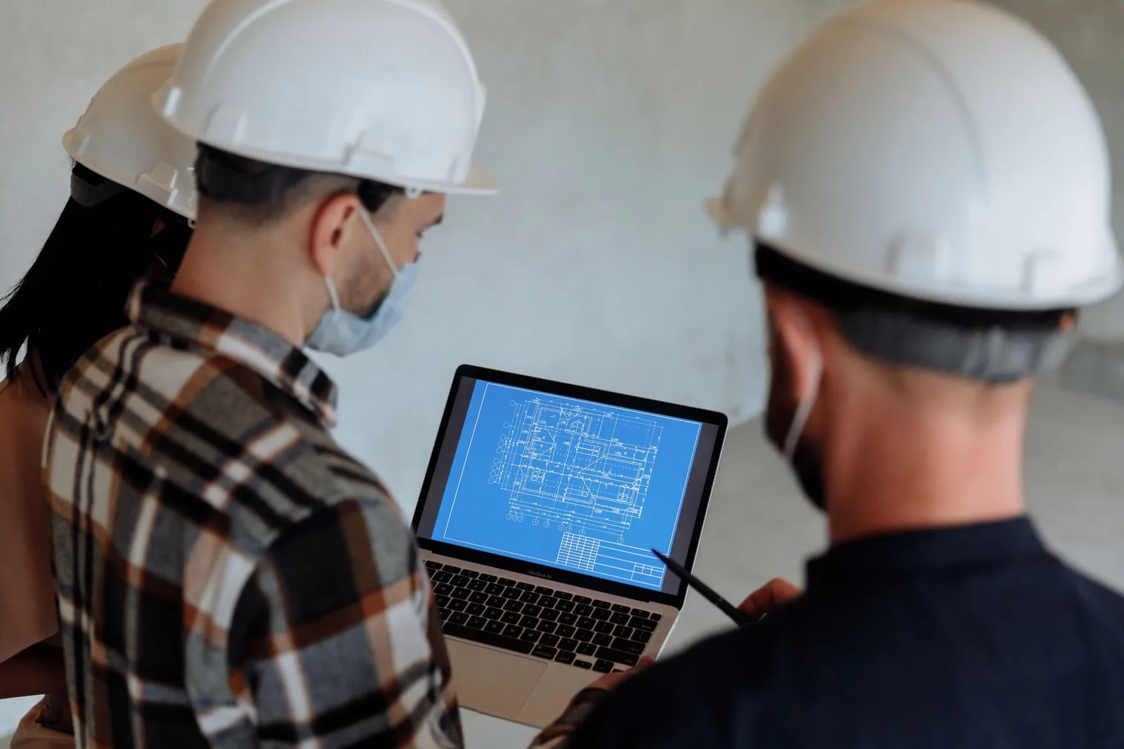 Construction professionals in hard hats reviewing a website on a laptop