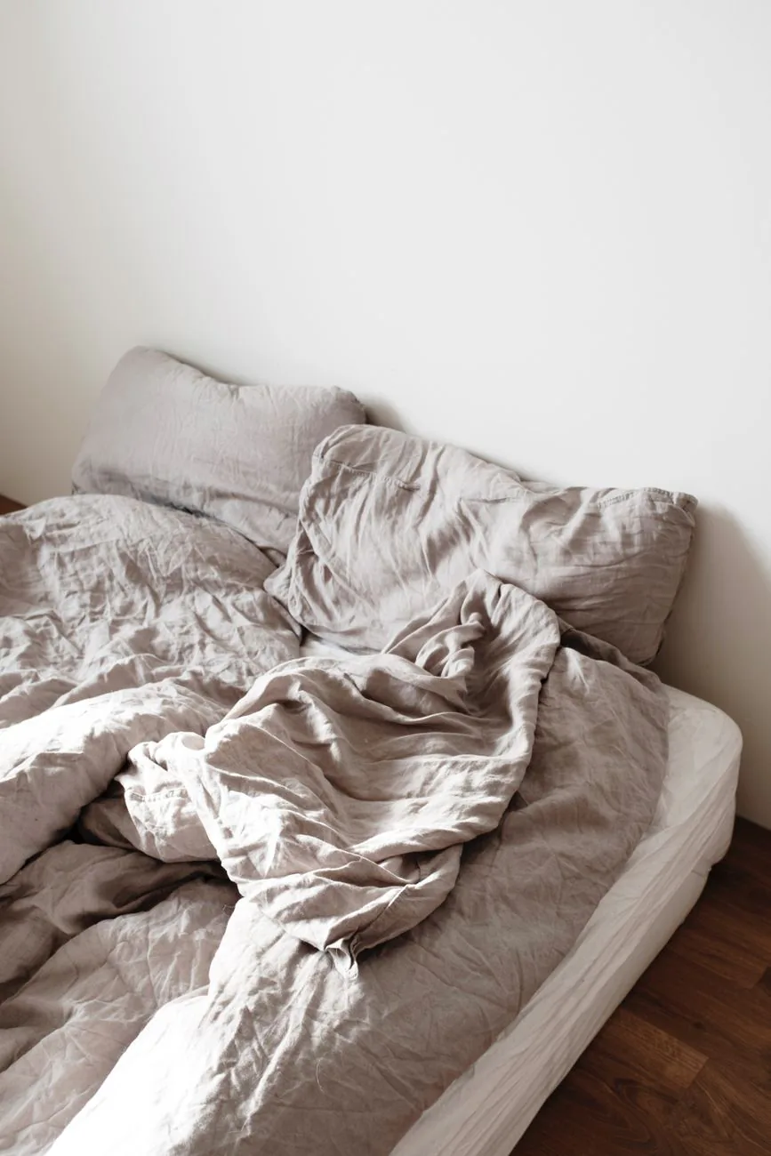 Soft linen bedding in a minimalist bedroom, in the calm neutral style Brooklinen uses