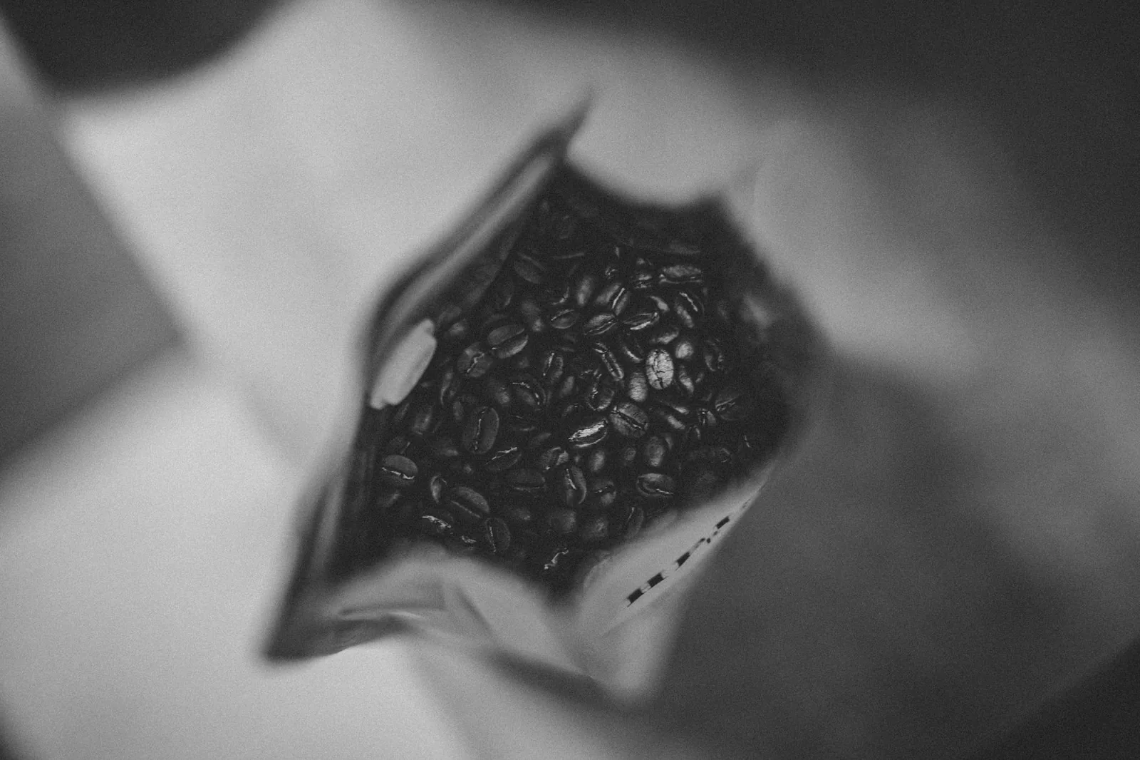 Coffee beans in a bag shot in moody black and white, matching Death Wish Coffee's bold identity