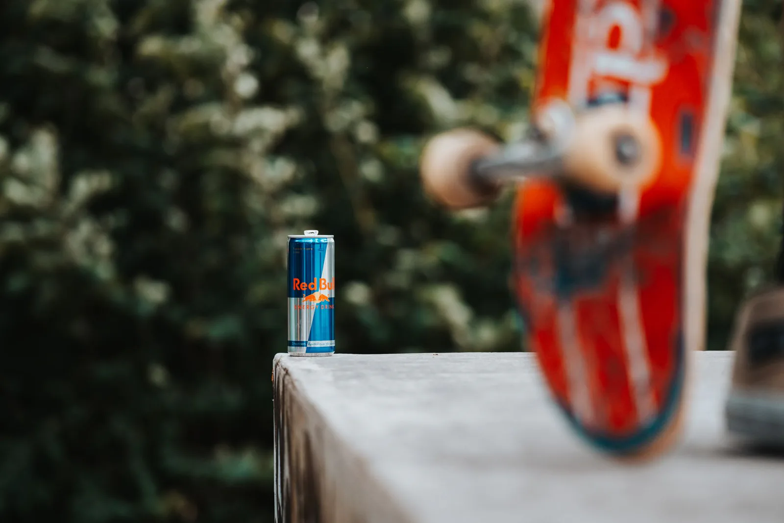 Skateboard in motion beside an energy drink can, in the extreme-sports style Red Bull is known for
