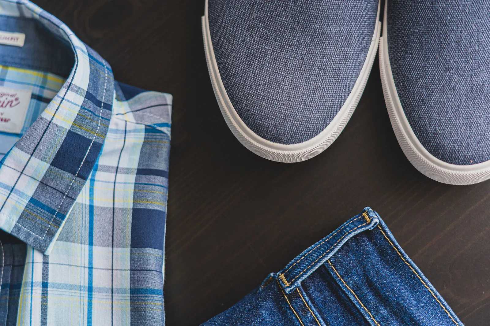 Flat lay of men's denim and casual clothing, in the crafted menswear style Taylor Stitch is known for