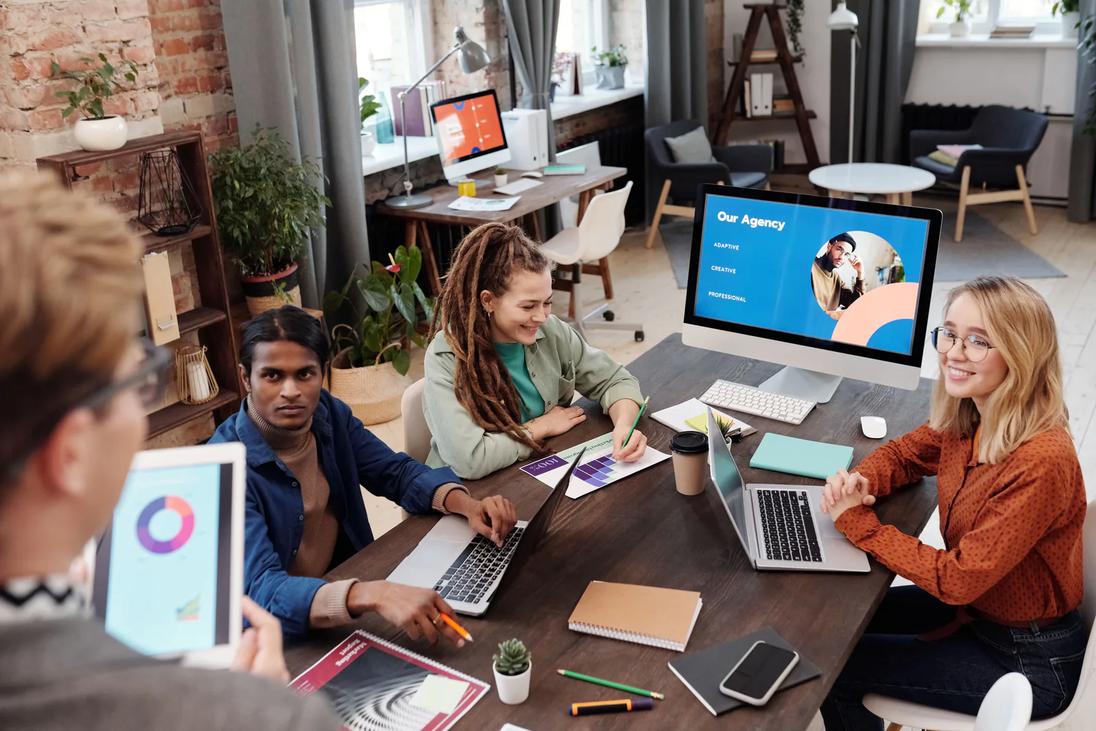 Diverse team of web designers collaborating around laptops in a bright modern studio