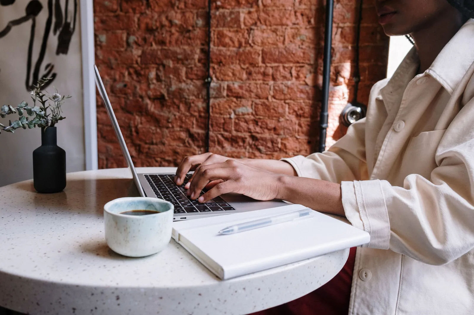 Person writing a blog article on a laptop in a café